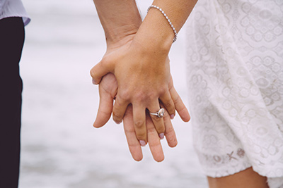γυναικείο χέρι με ριβιέρα και μονόπετρο δαχτυλίδι κρατάει αντρικό χέρι